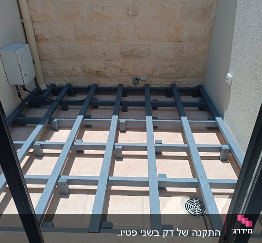 מבנה מתכת על רצפת מרפסת עם קיר אבן